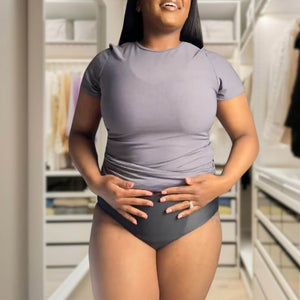 Woman smiling in Hem support wear, gently holding her abdomen to show pelvic floor comfort and fit.