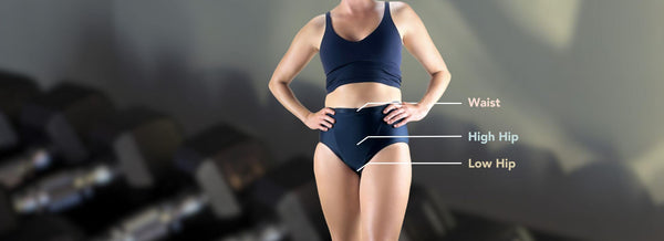 Woman wearing Hem Support Wear's black heigh waisted support garment with labels showing how to measure waist, high hip, and low hip for best Hem fit.